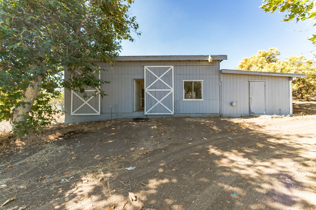 a white barn with two doors and a tree in front of it