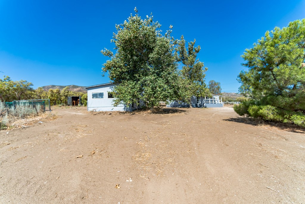 a small white house sitting in the middle of a dirt field