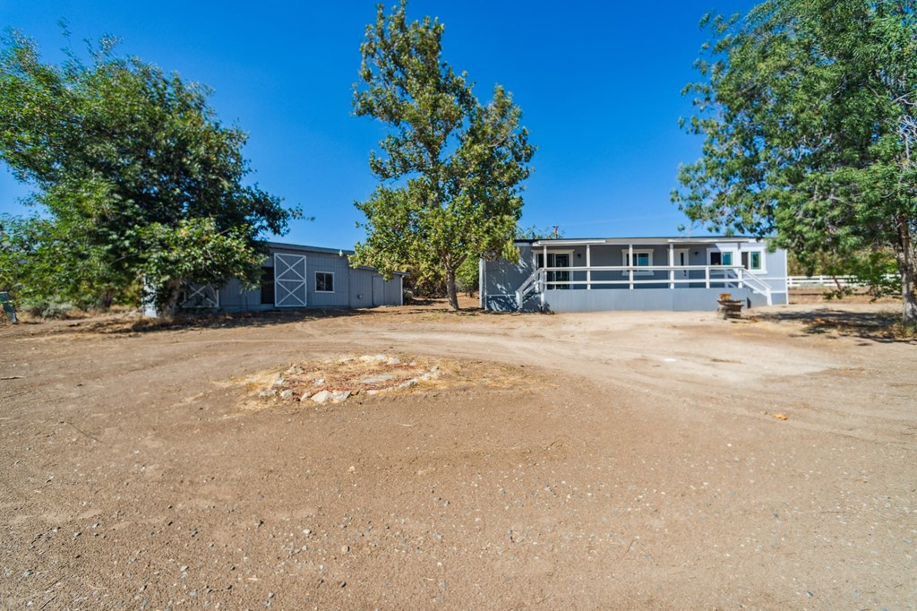 the front of a house with a gravel driveway and trees