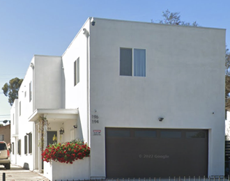 the front of a white building with a garage door