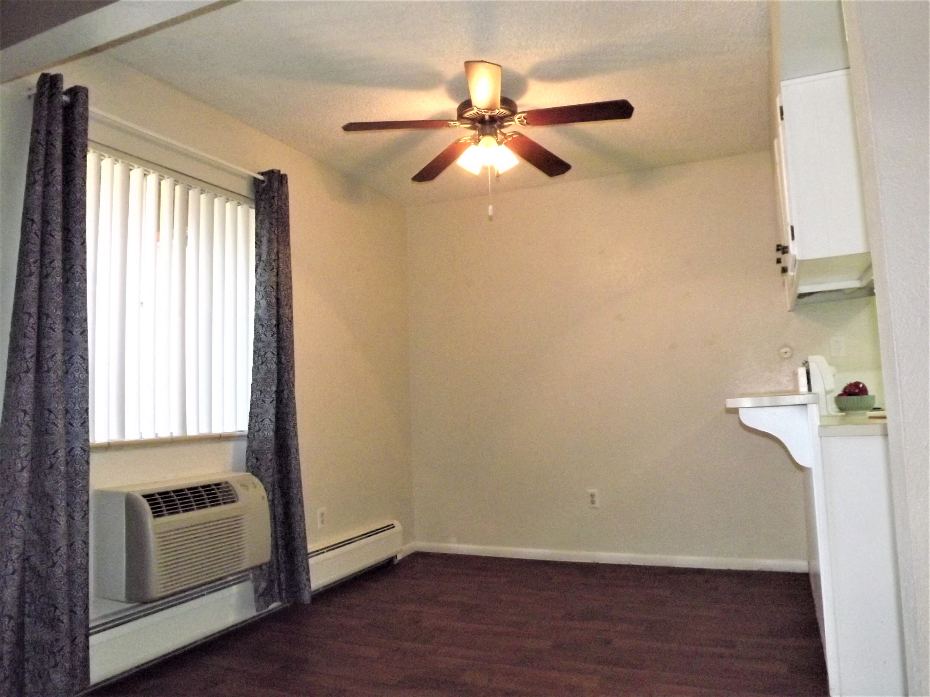 an empty living room with a ceiling fan and a window