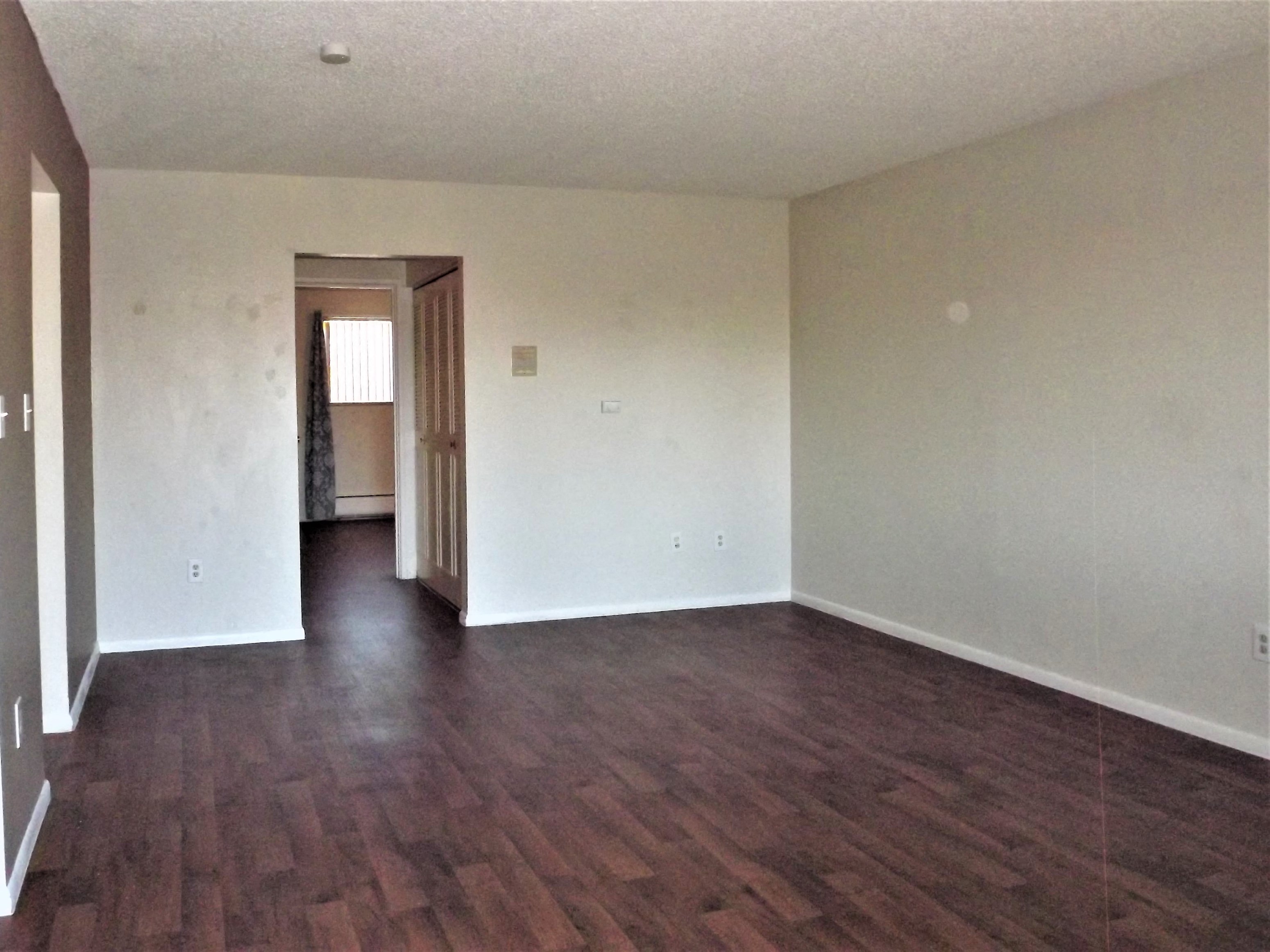 an empty living room with white walls and wood floors