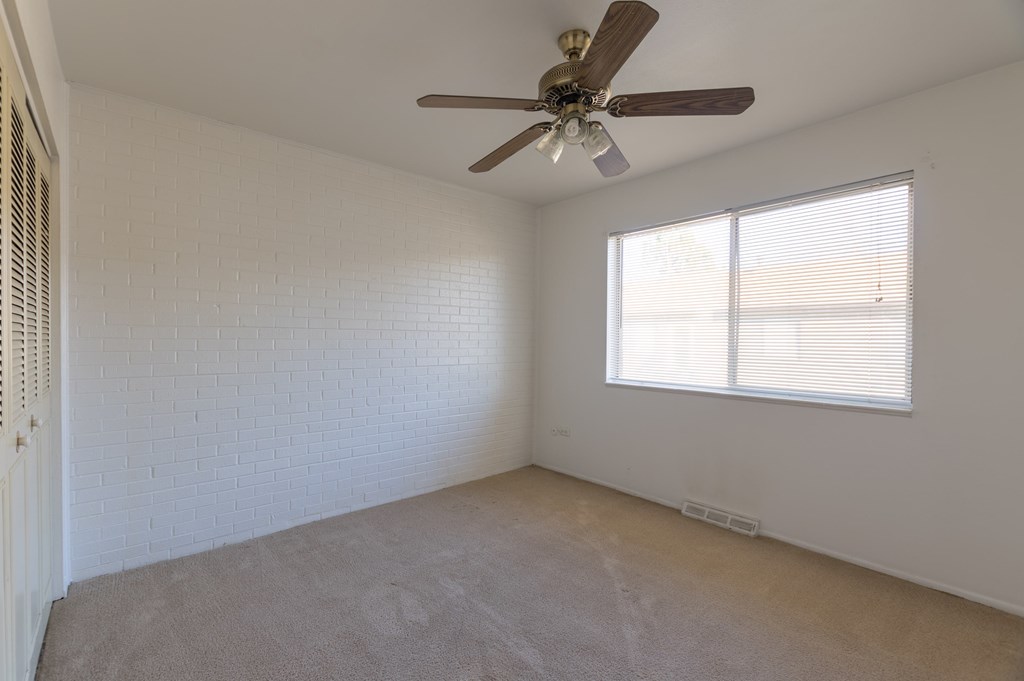 an empty room with a ceiling fan and a window