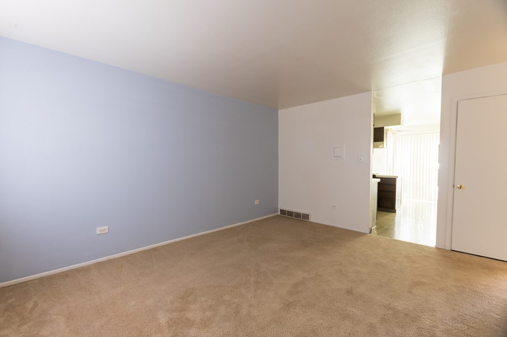 an empty living room with a blue wall and carpet