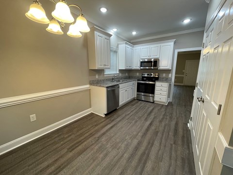 A kitchen with white cabinets and a grey floor.