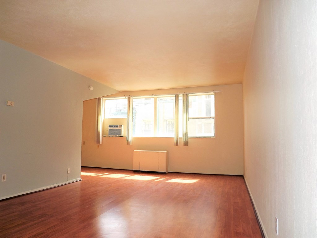 an empty living room with wood floors and a window