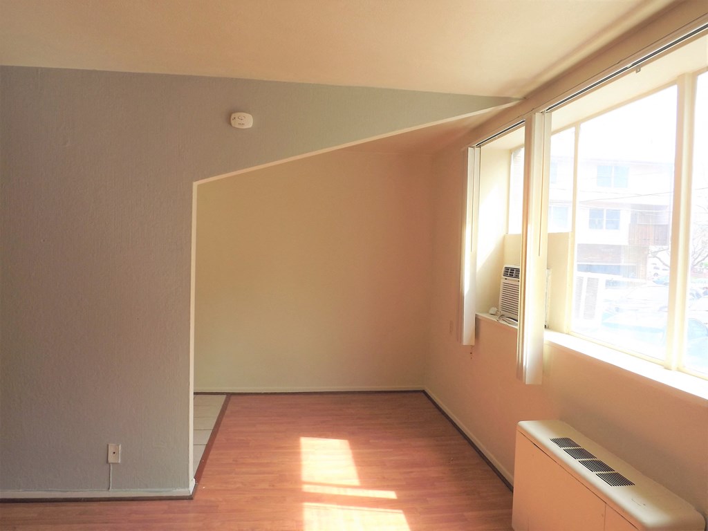 an empty living room with wood floors and a window