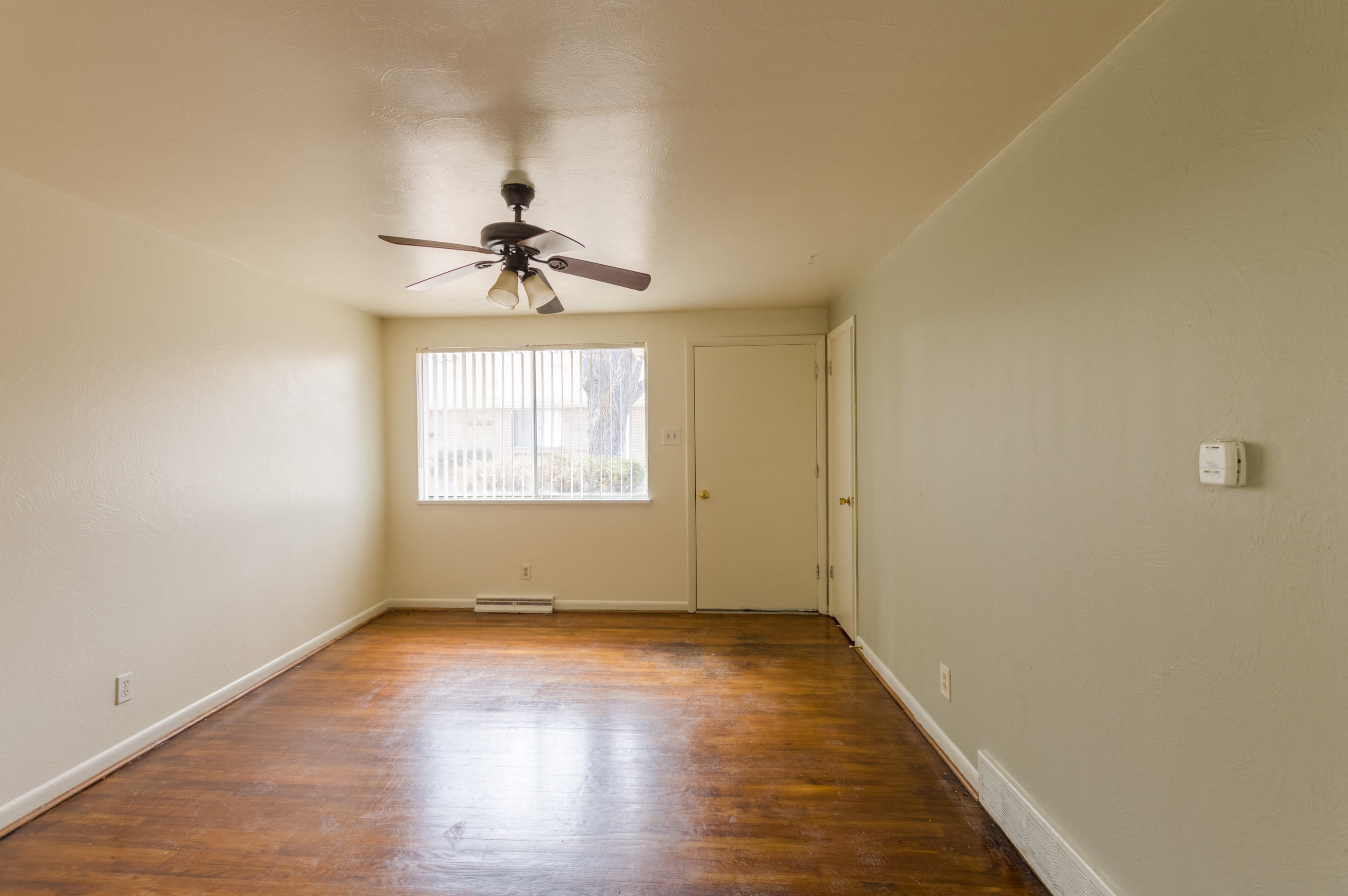A room with a ceiling fan and wooden floors.