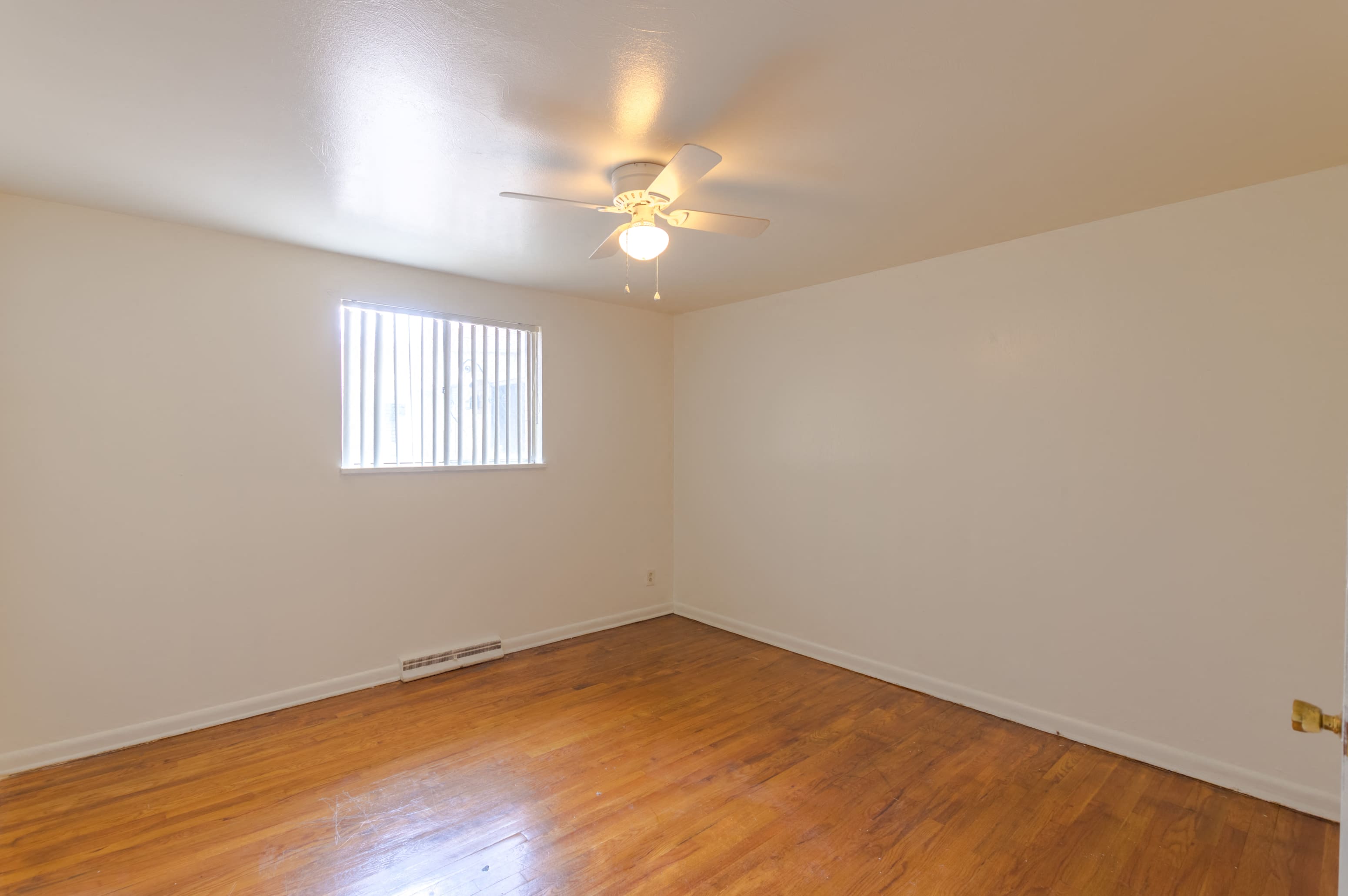 A room with a ceiling fan and a window with blinds.