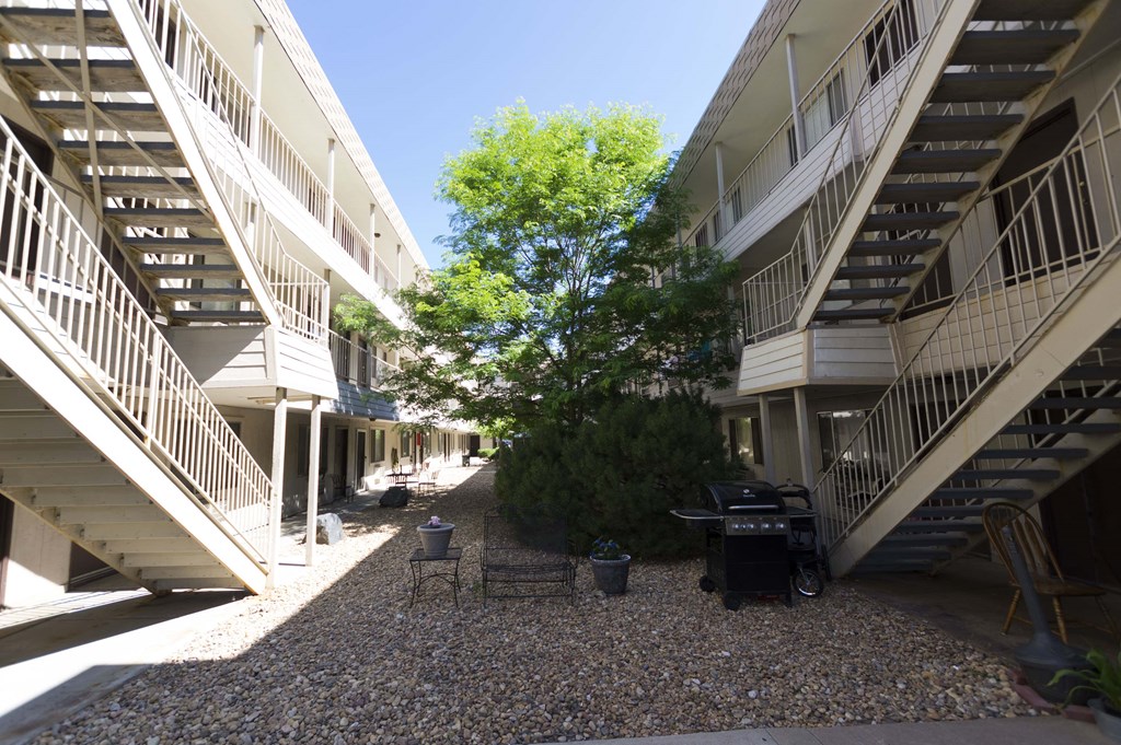 the courtyard between the buildings has a grill and a tree