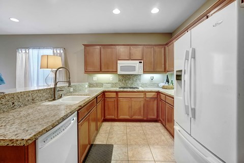 A kitchen with brown cabinets and a white refrigerator.
