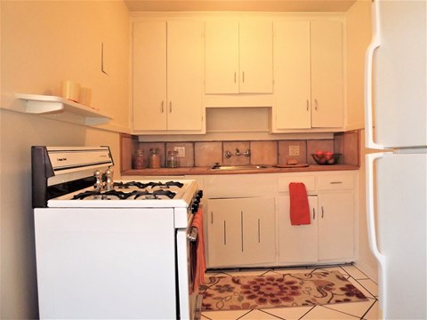 a small kitchen with white cabinets and a stove and refrigerator