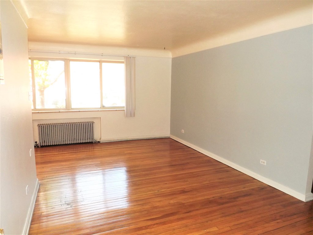 an empty living room with wooden floors and a window