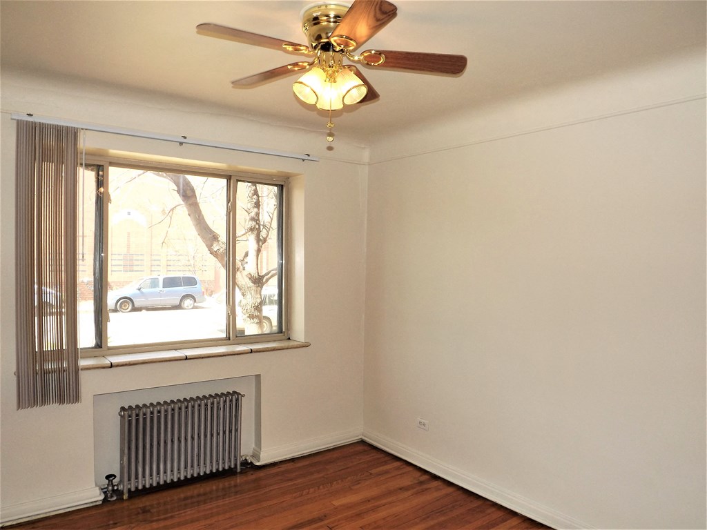 an empty living room with a ceiling fan and a window