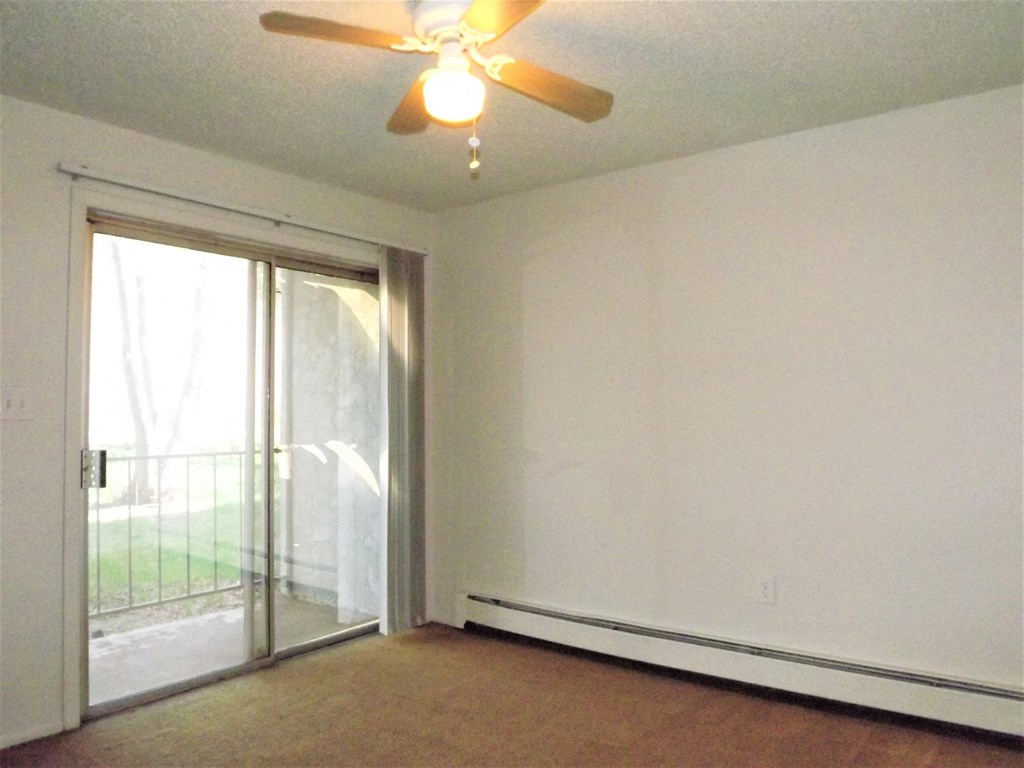 an empty living room with a ceiling fan and a sliding glass door