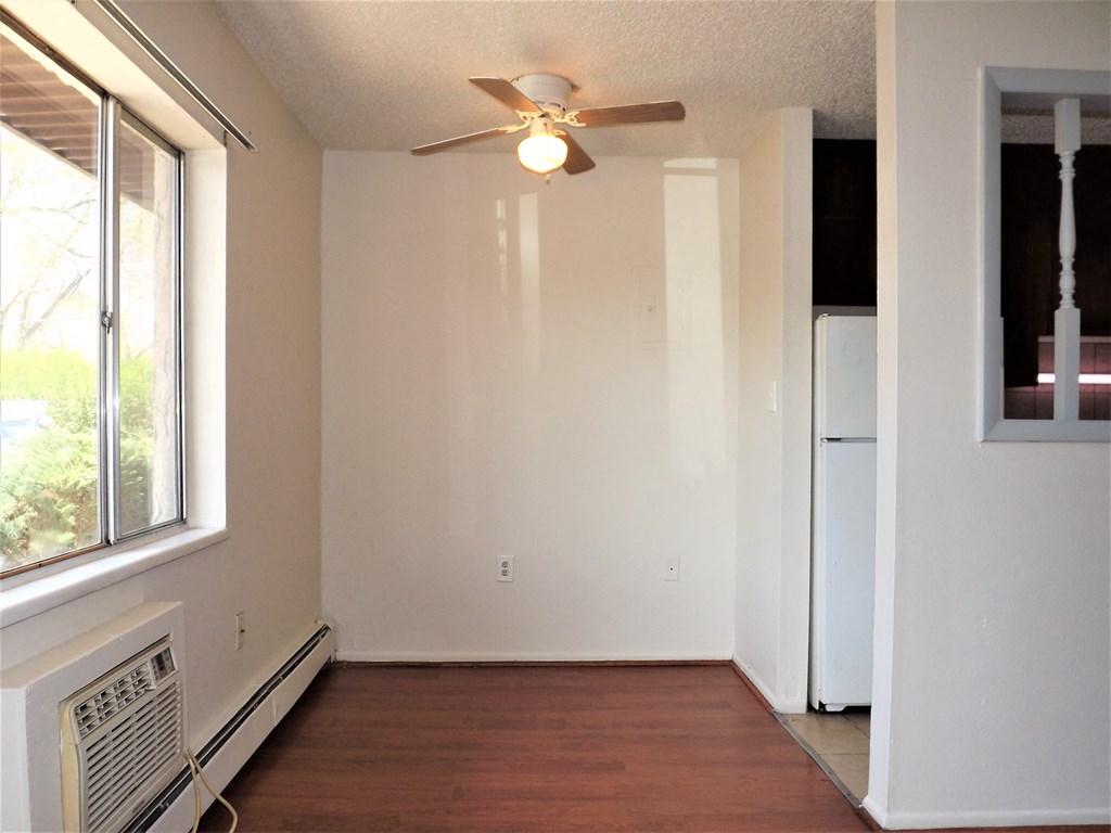 an empty living room with a ceiling fan and a window