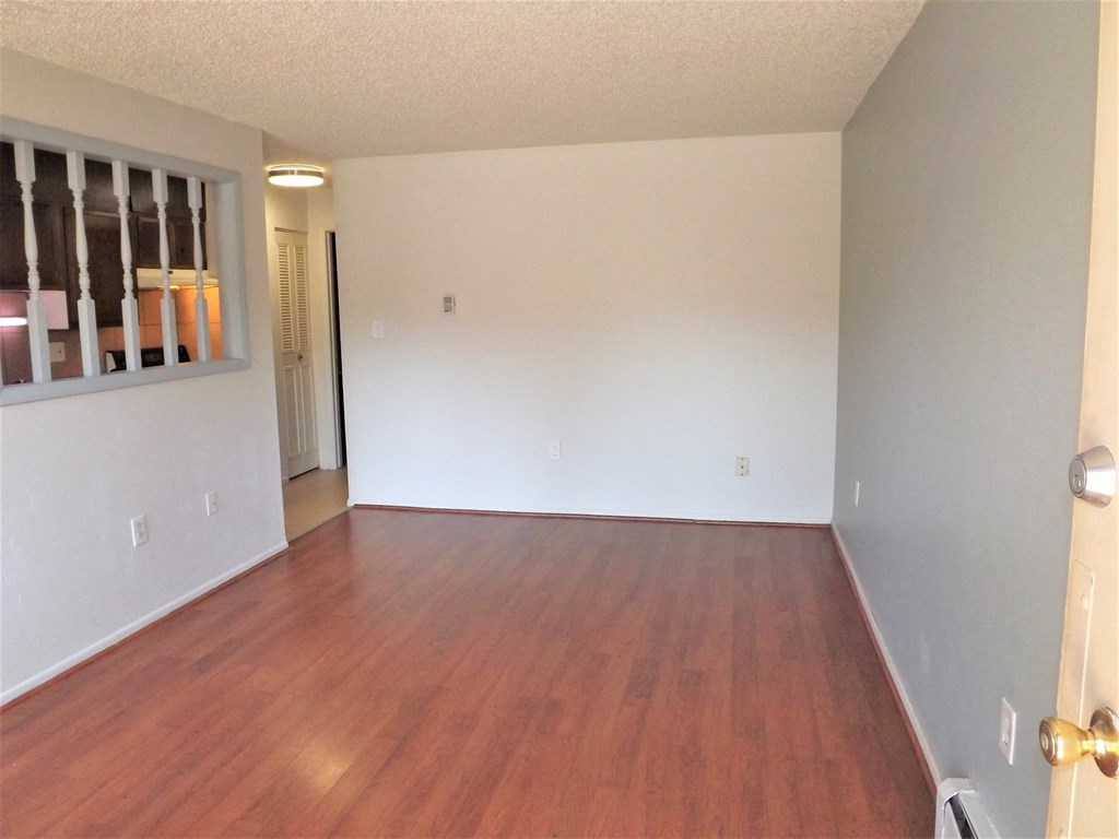 an empty living room with wood flooring and white walls