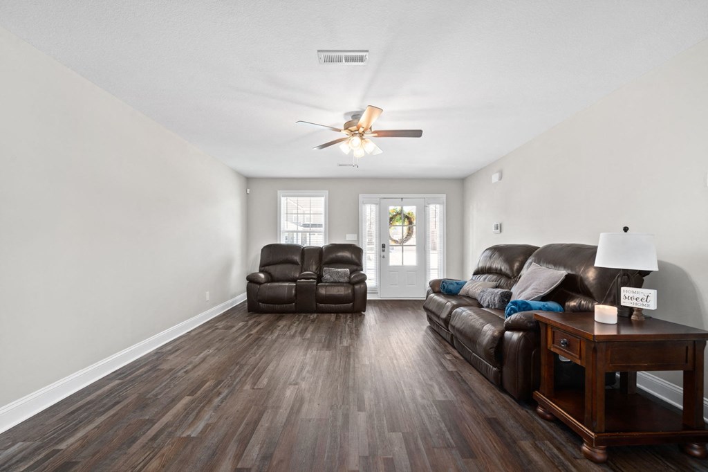 a living room with two couches and a table and a ceiling fan