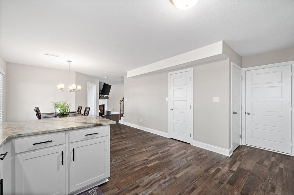 an open kitchen and living room with white cabinets and a counter top