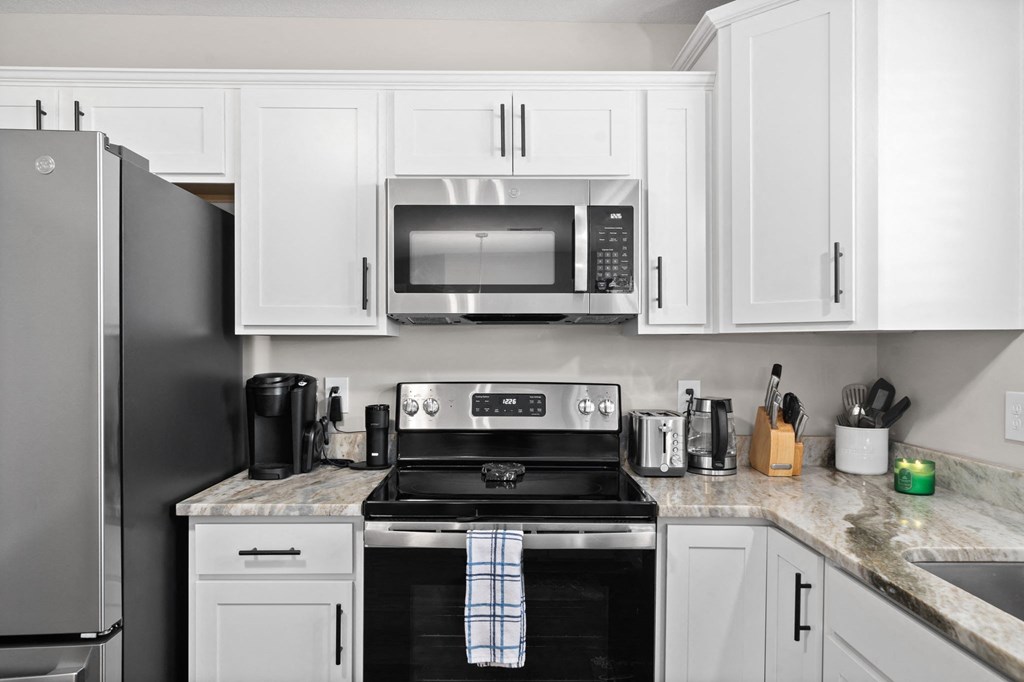 a kitchen with white cabinets and a stove and a microwave