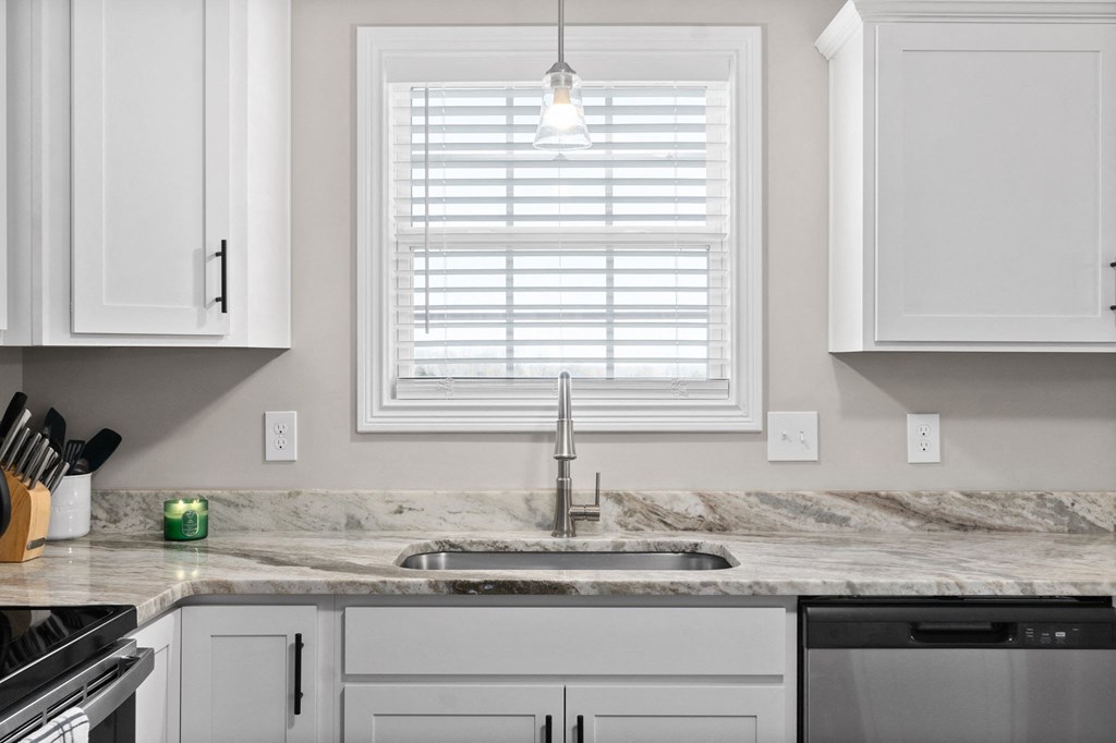 a kitchen with white cabinets and a sink and a window