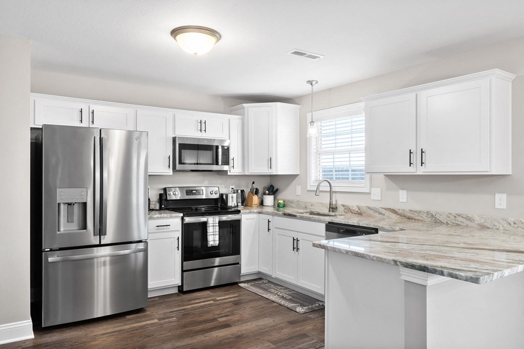 a white kitchen with stainless steel appliances and marble counter tops