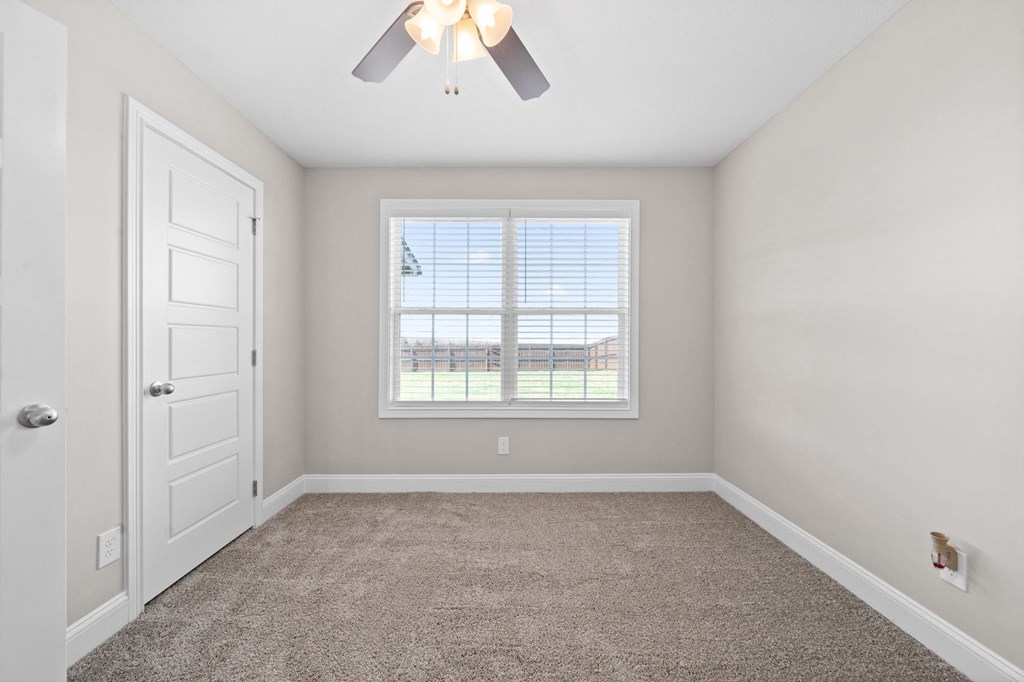 an empty bedroom with a window and a ceiling fan