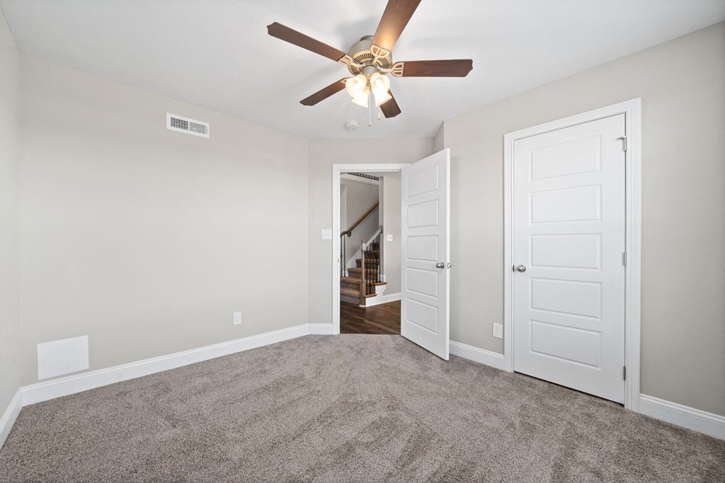 a bedroom with a ceiling fan and a door to a hallway