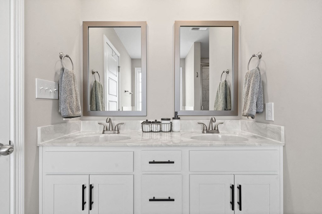 a white bathroom with two sinks and two mirrors