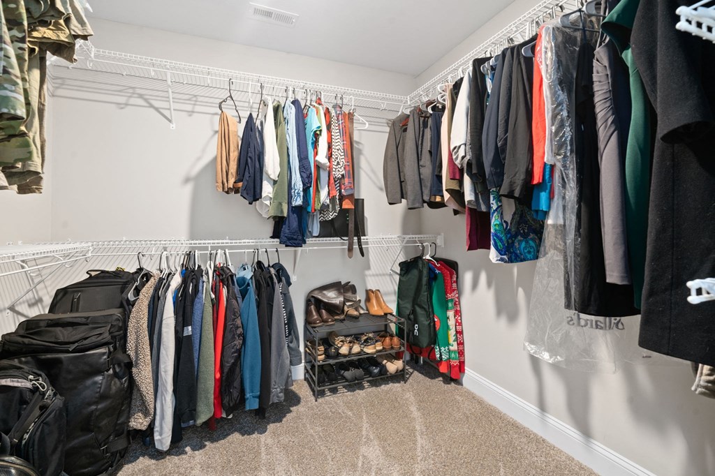 a closet with a rack of clothes and a suitcase on the floor