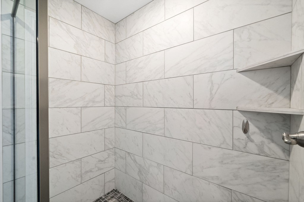 a shower with white marble tiles in a bathroom