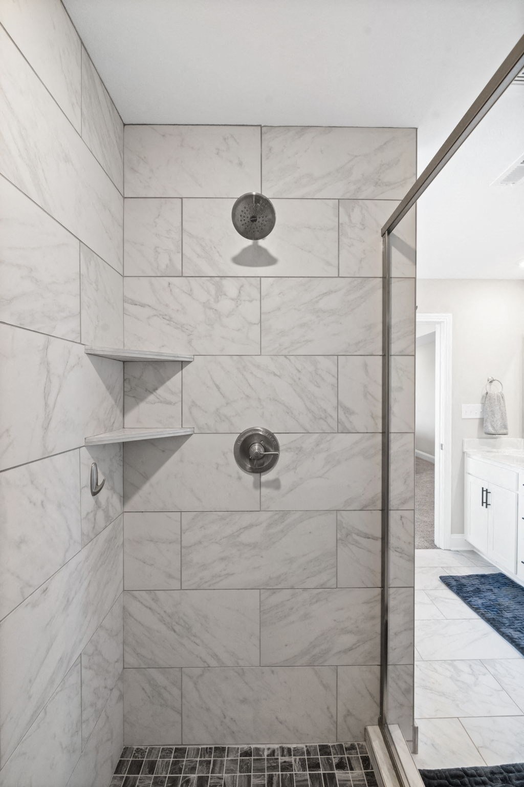 a large shower with marble tiles in a bathroom
