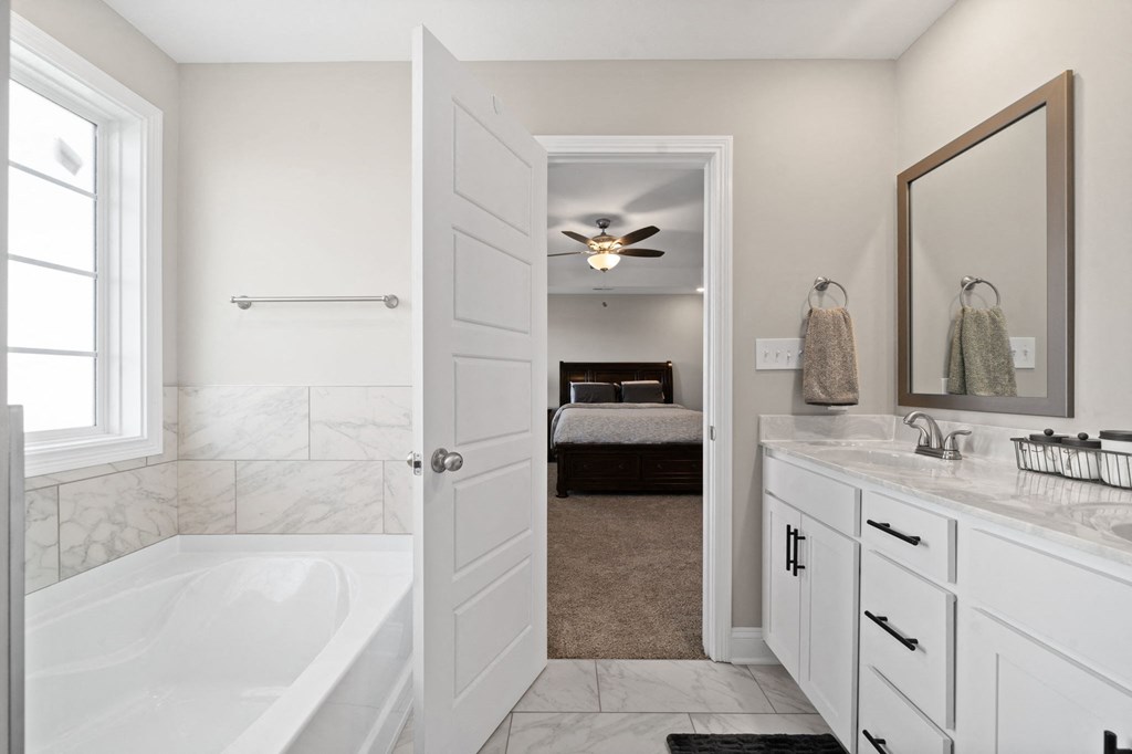 a white bathroom with a tub and a sink and a mirror