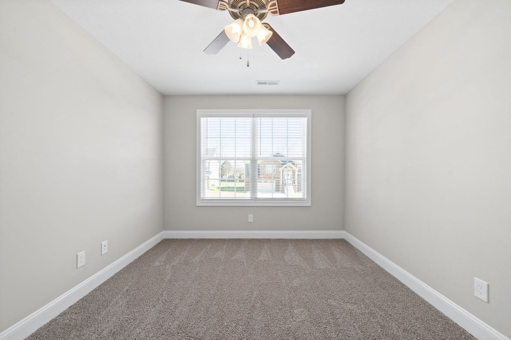 an empty living room with a ceiling fan and a window