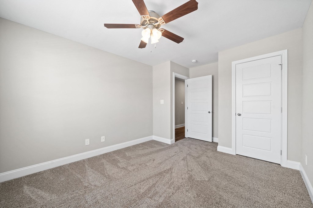 a bedroom with a ceiling fan and a door to a closet