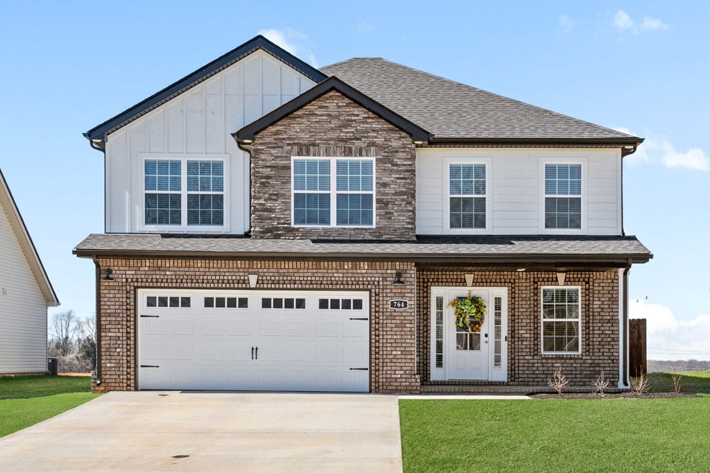 a brick house with a white garage door in front of a lawn