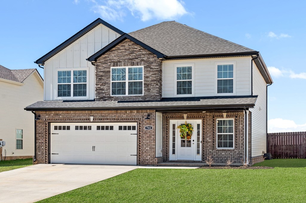a brick house with a white garage door in front of a lawn