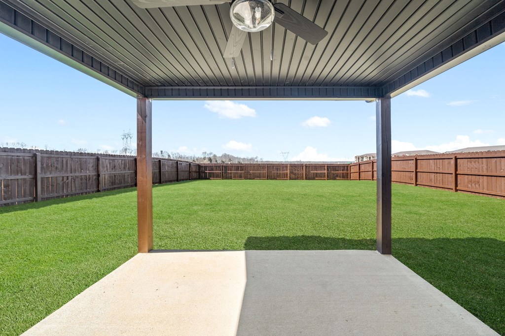 a covered patio with a lawn and a fence