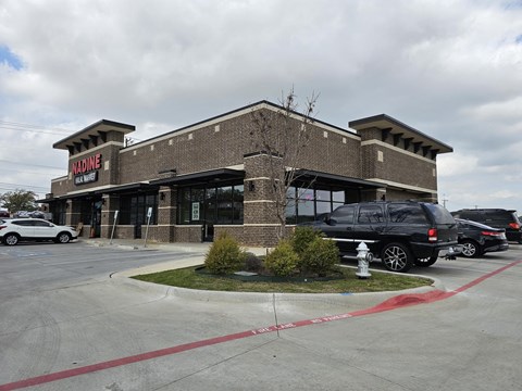A Madine storefront with a black SUV parked in front.