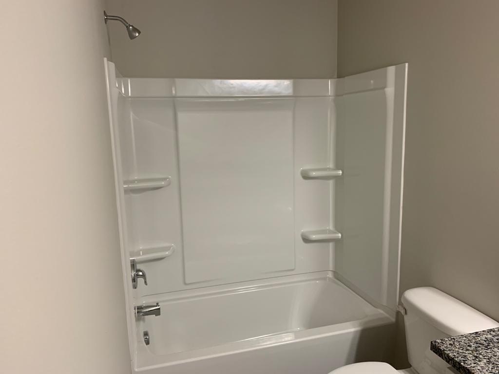 A white bathroom with a walk-in shower and toilet.