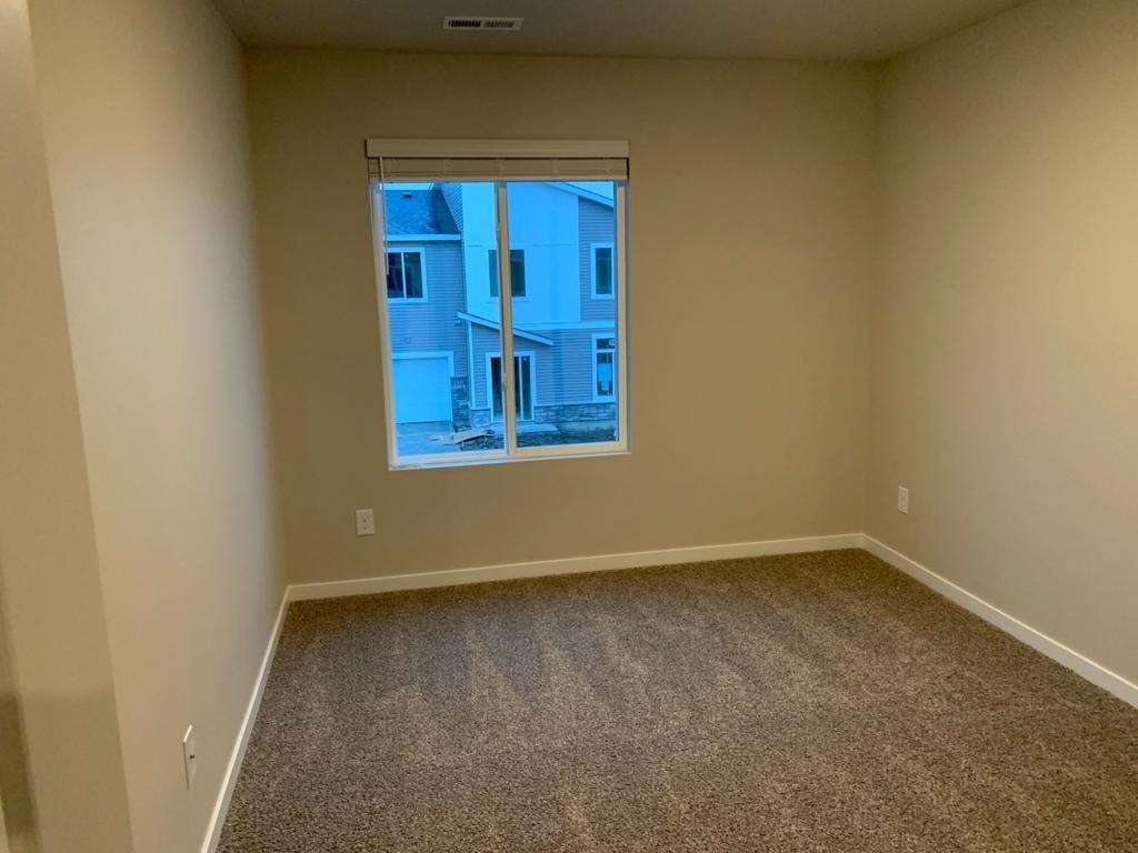 A room with a carpeted floor and a window showing a view of a building outside.