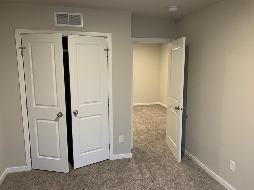 A room with two white doors and carpeted floor.