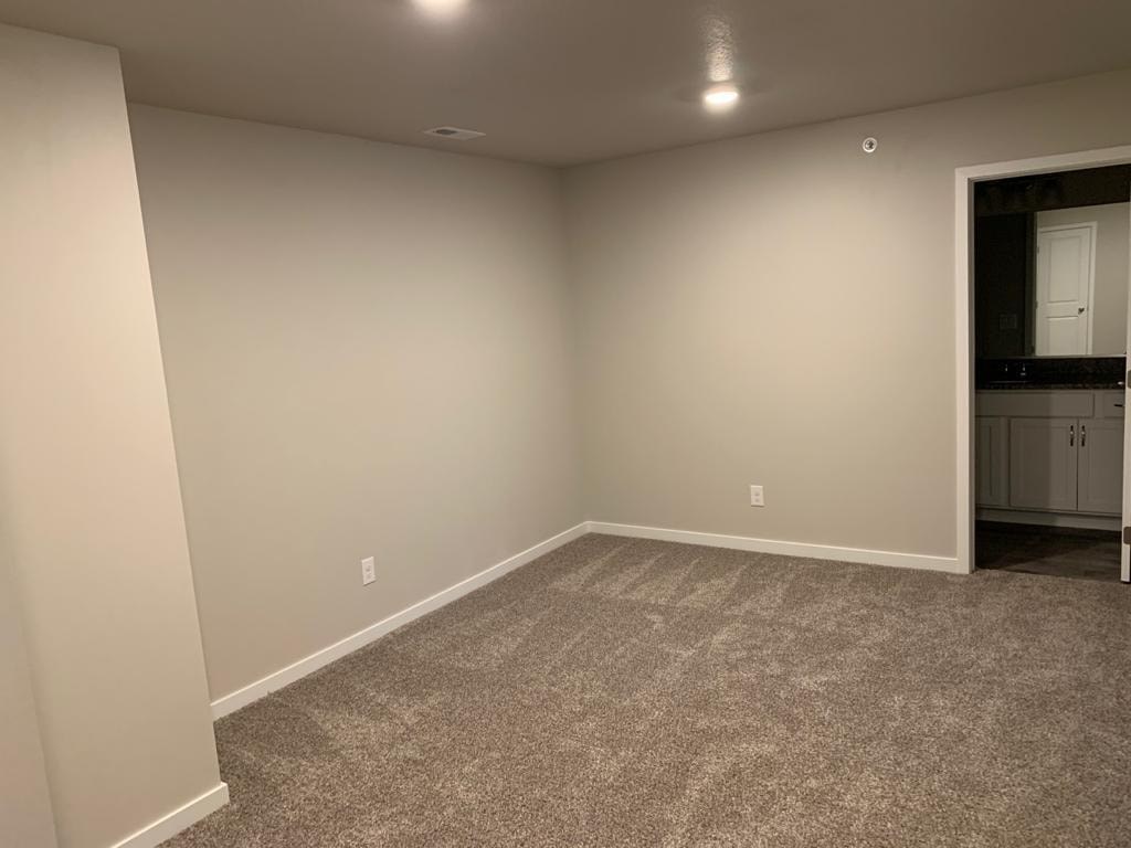 A room with a carpeted floor and a door on the right side.