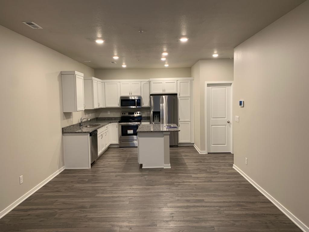 A kitchen with white cabinets and a refrigerator.
