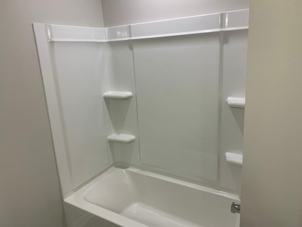 A white bathroom with a shower and shelves.