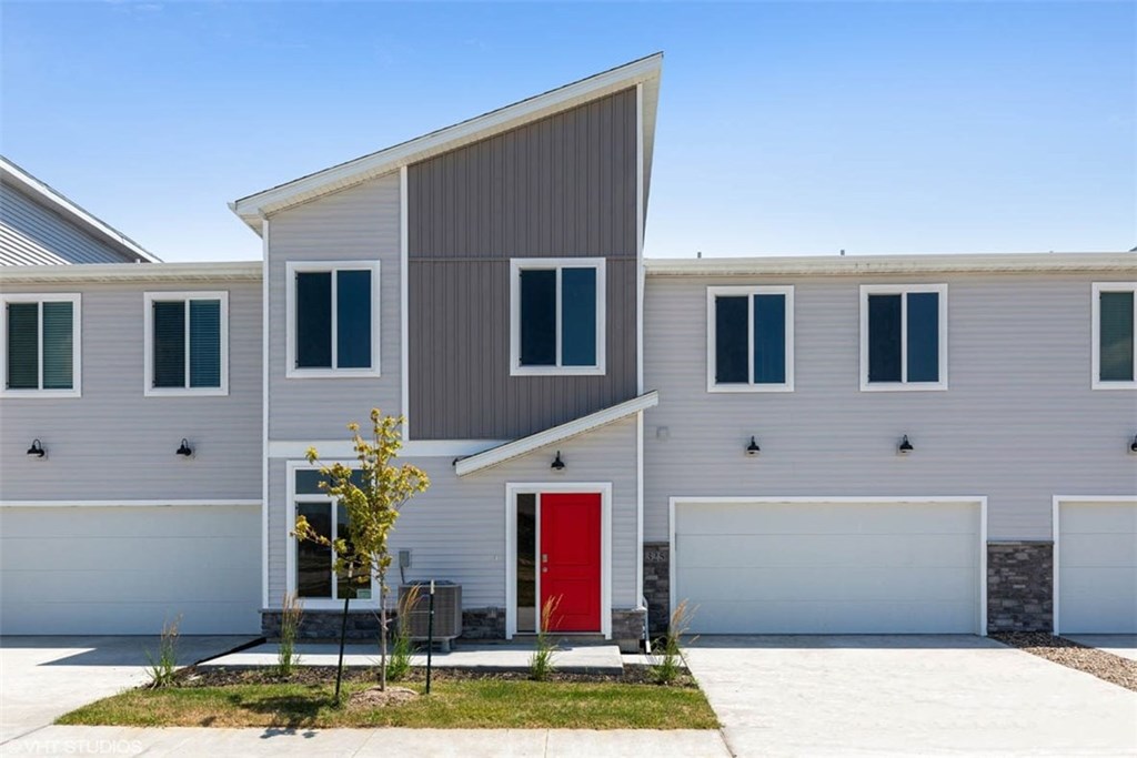 A modern house with a red door stands out against a clear blue sky.