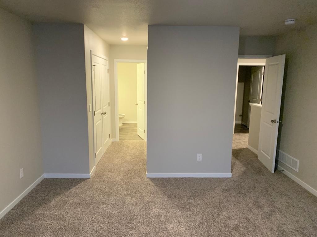 A hallway with carpeted floors and white walls.