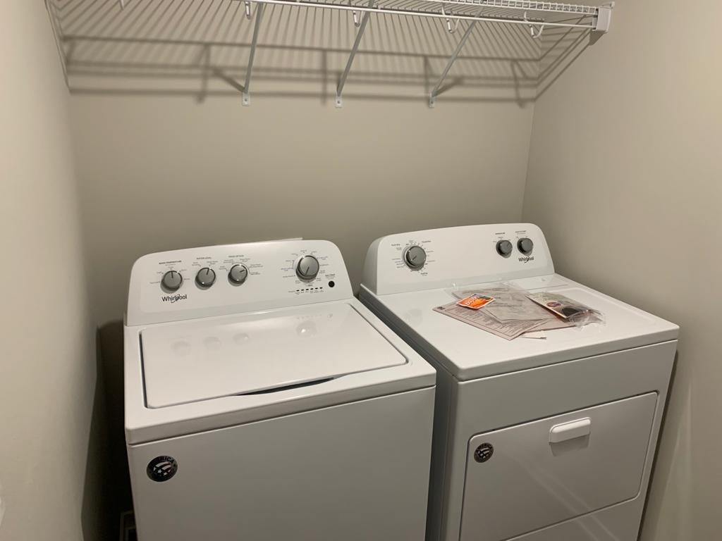 Two white front loading washing machines in a laundry room.