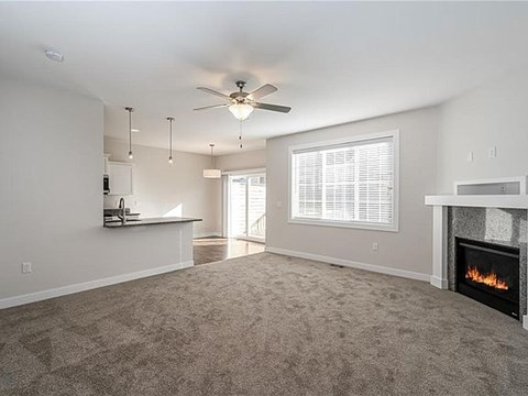 A living room with a fireplace and a ceiling fan.