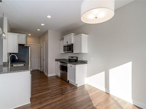 A kitchen with white cabinets and a black countertop.